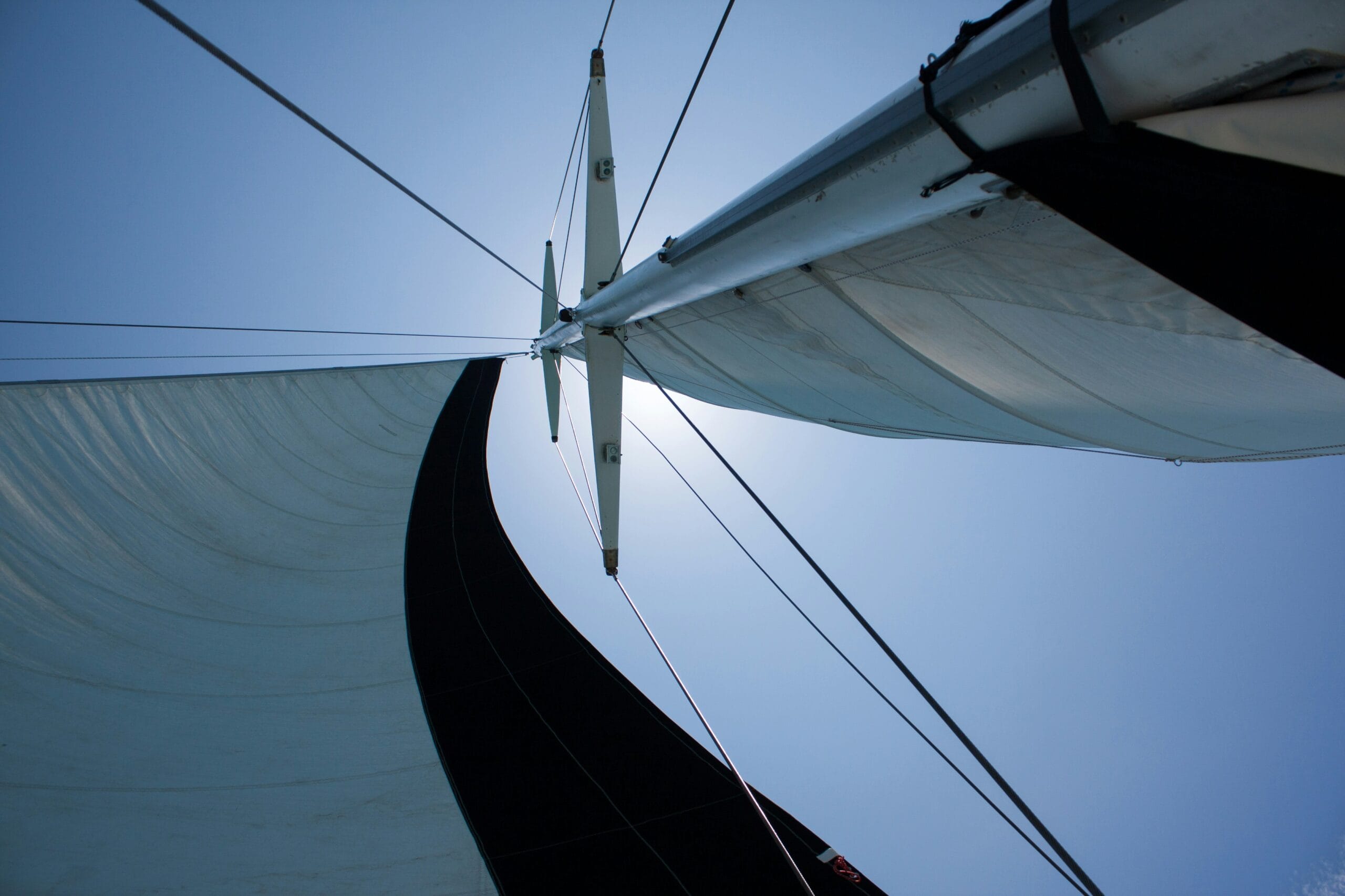 Segel und Mast eines Segelboots vor blauem Himmel
